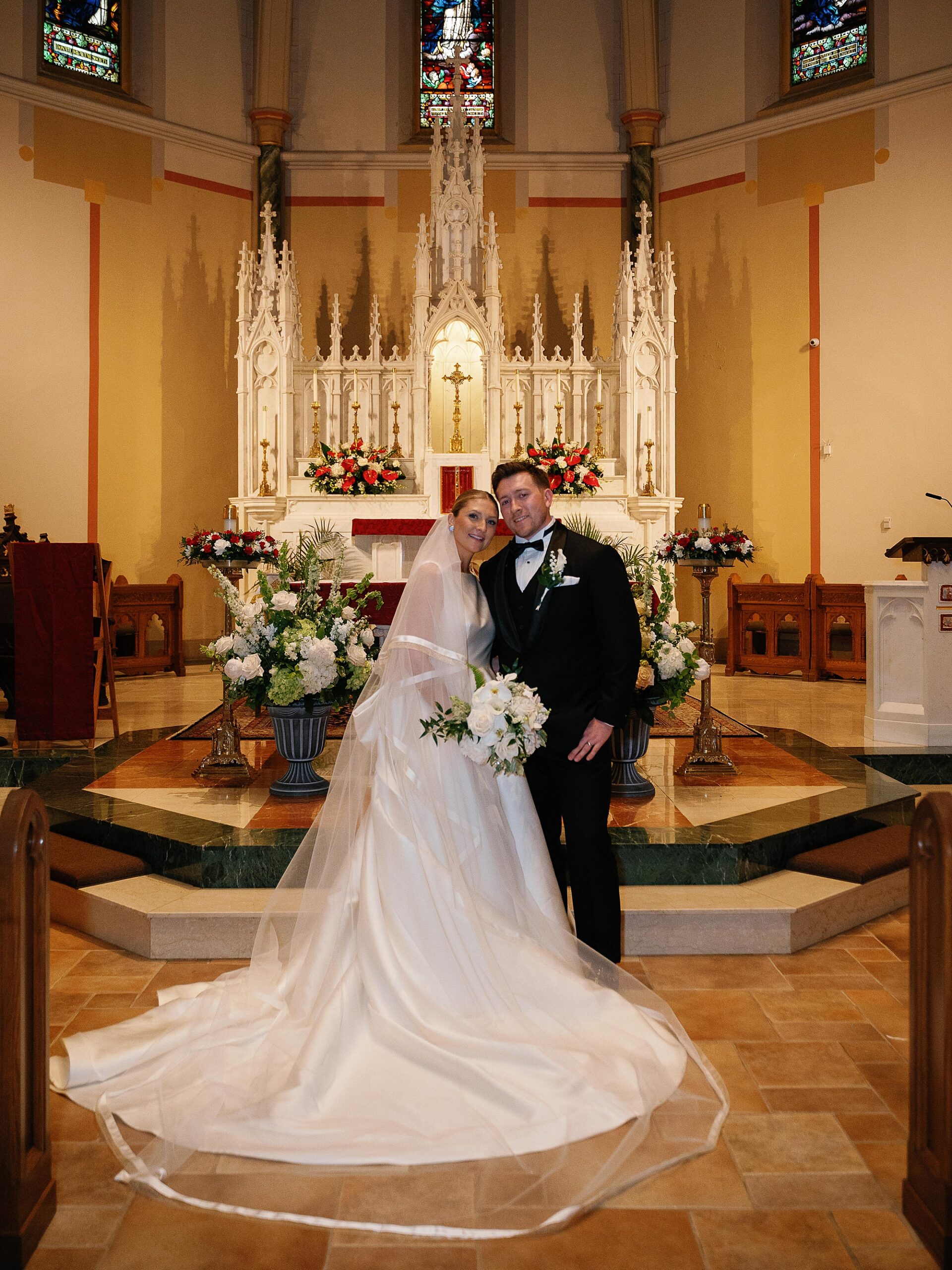newlyweds hug in front of alter inside Immaculate Conception Church
