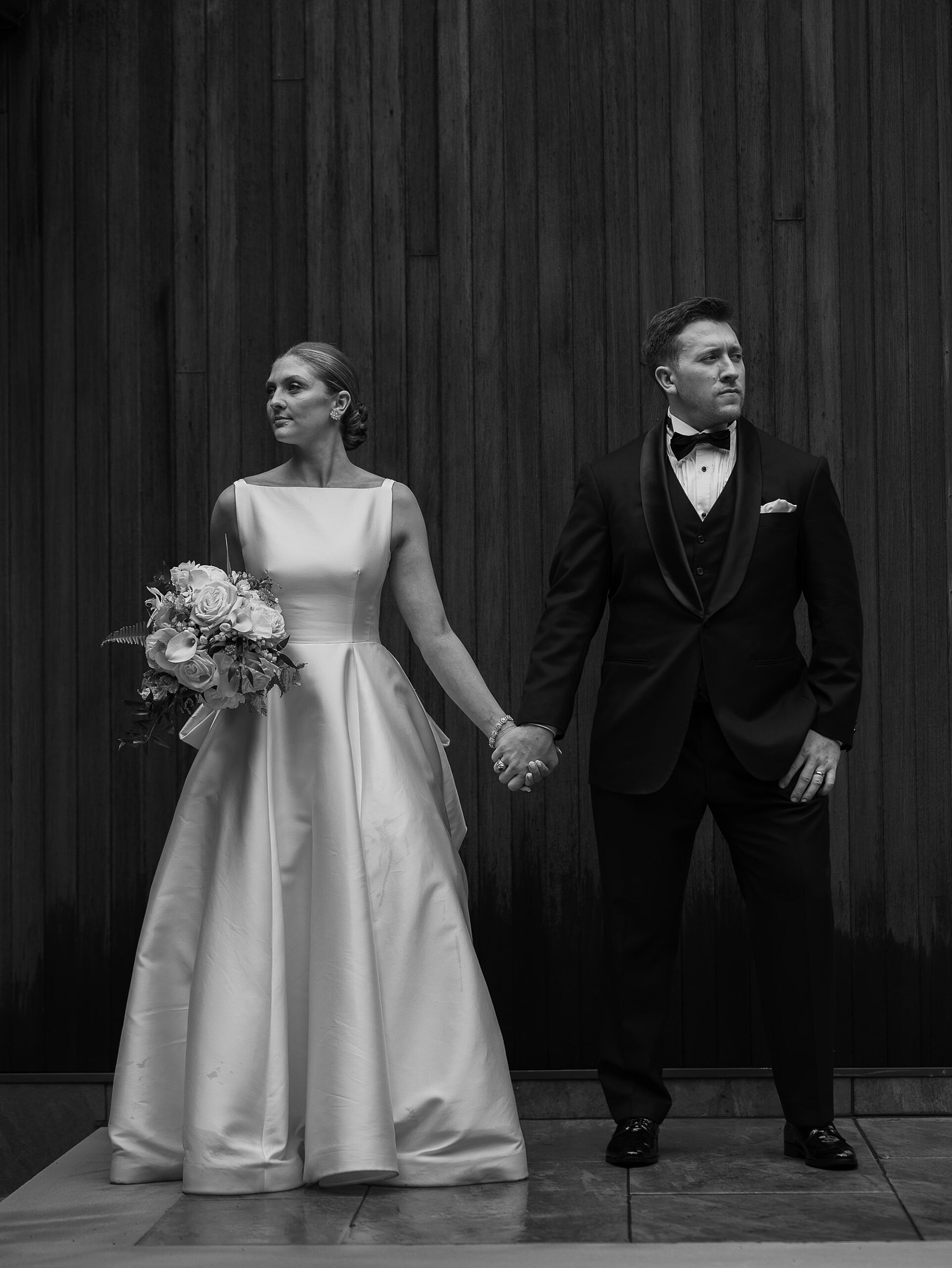 bride and groom hold hands in front of wooden door