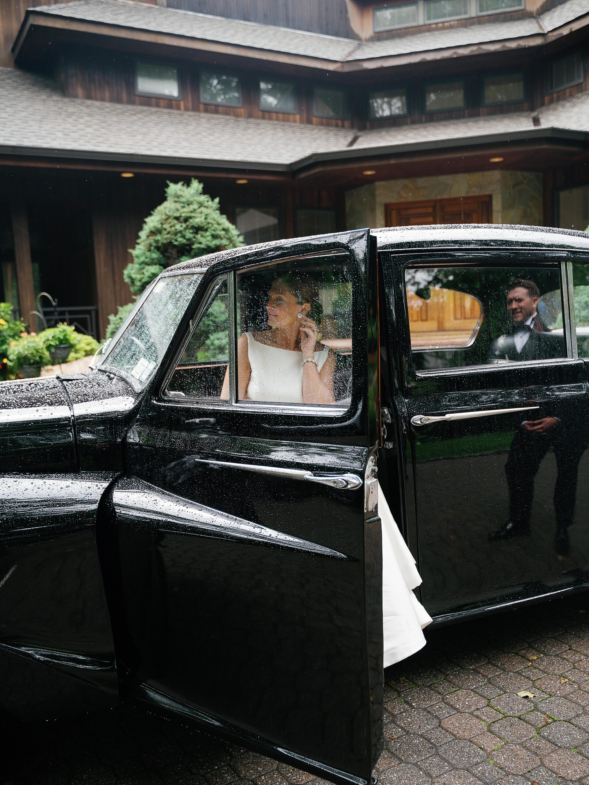 bride steps out of black classic car outside the Bronxville Field Club