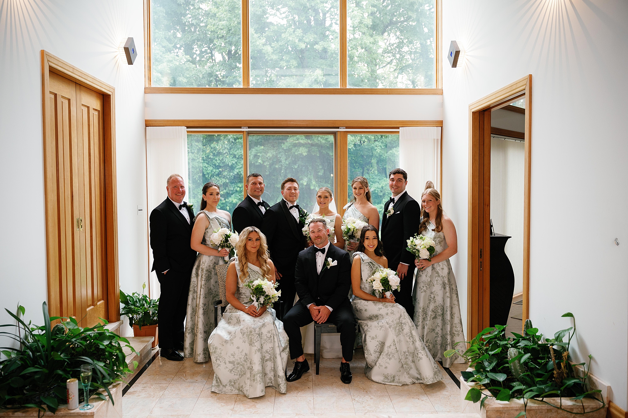bride and groom sit with wedding party inside Bronxville Field Club