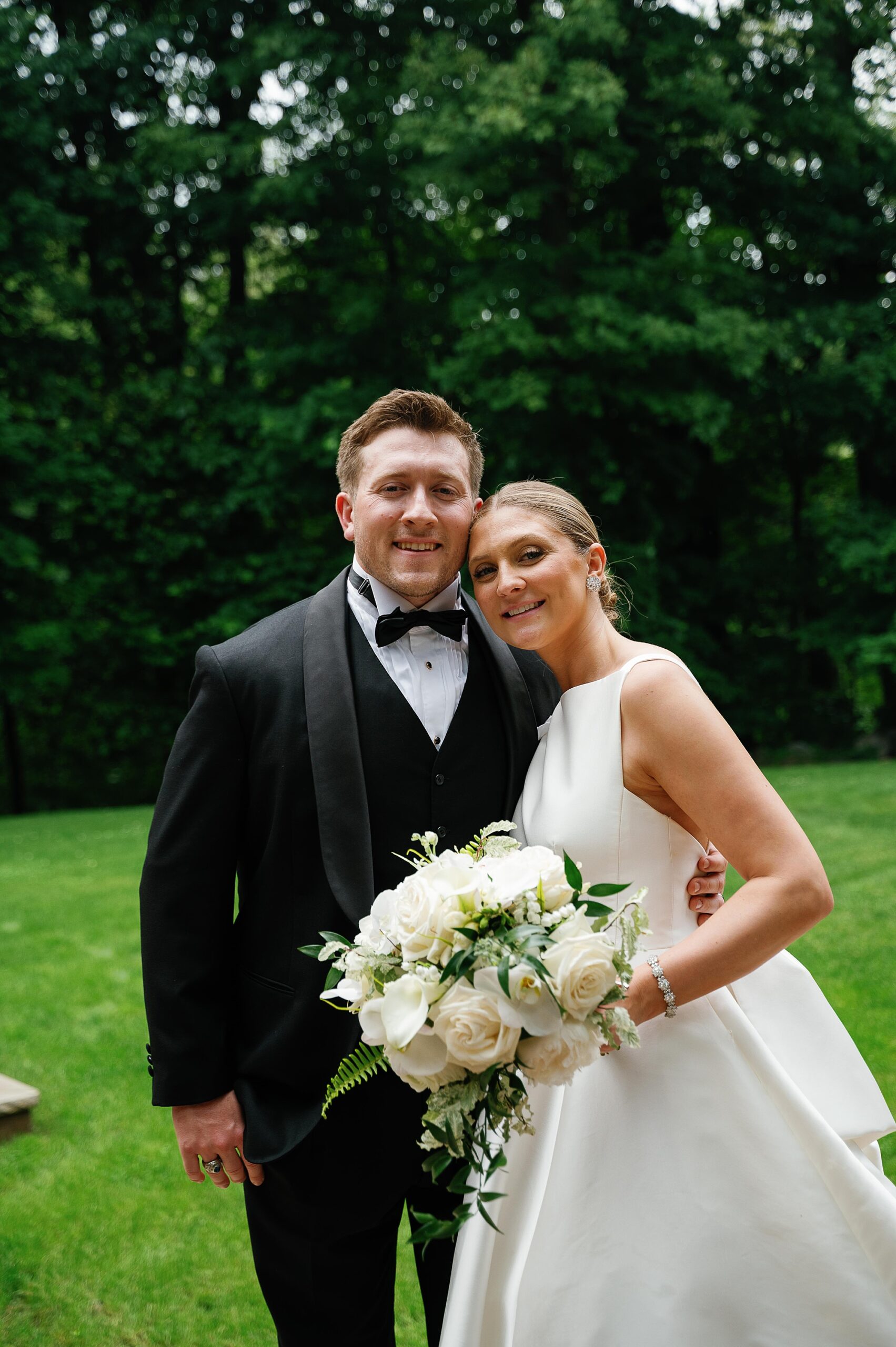 bride leans on groom's shoulder hugging during photos at the Bronxville Field Club