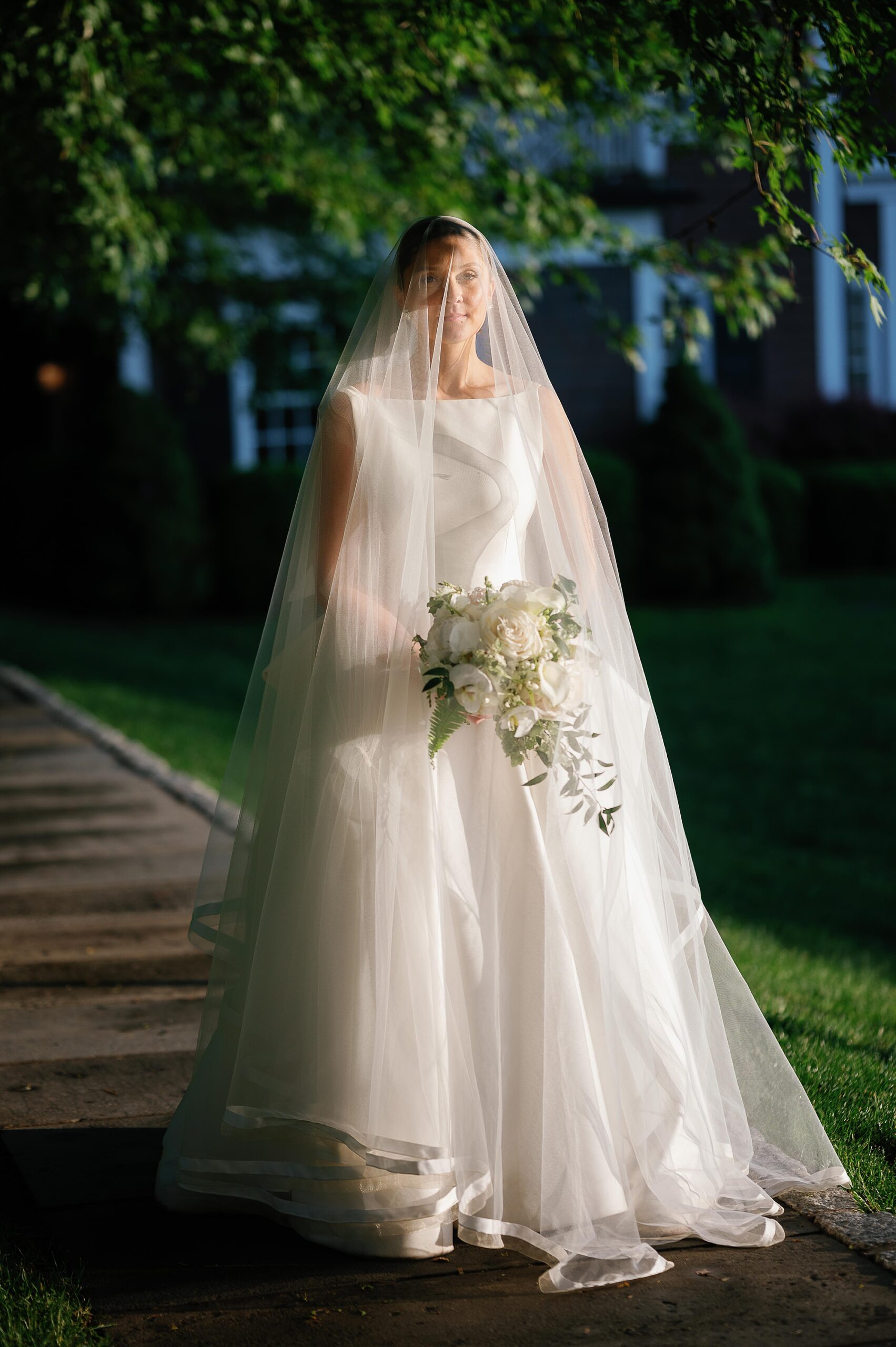 bride poses holding wedding bouquet under her veil