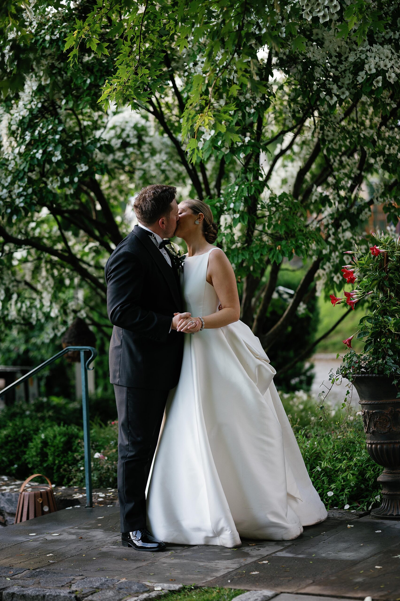 newlyweds kiss by trees in gardens of the Bronxville Field Club