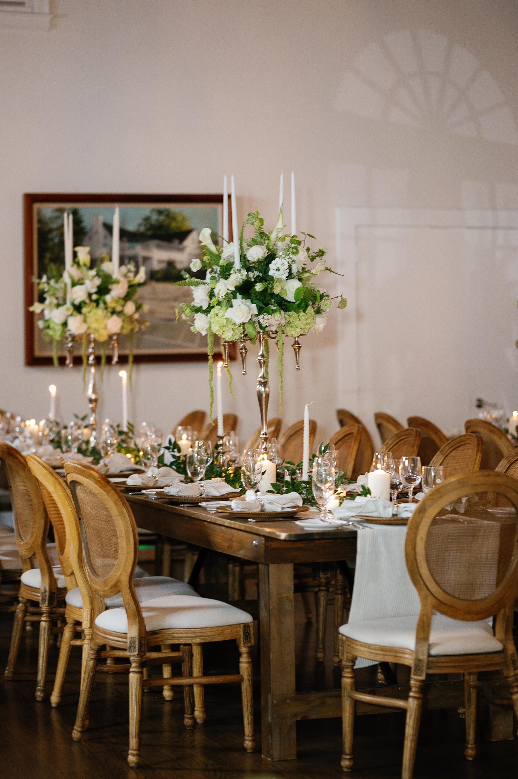 reception tables with white napkins, tall floral centerpieces and wooden tables